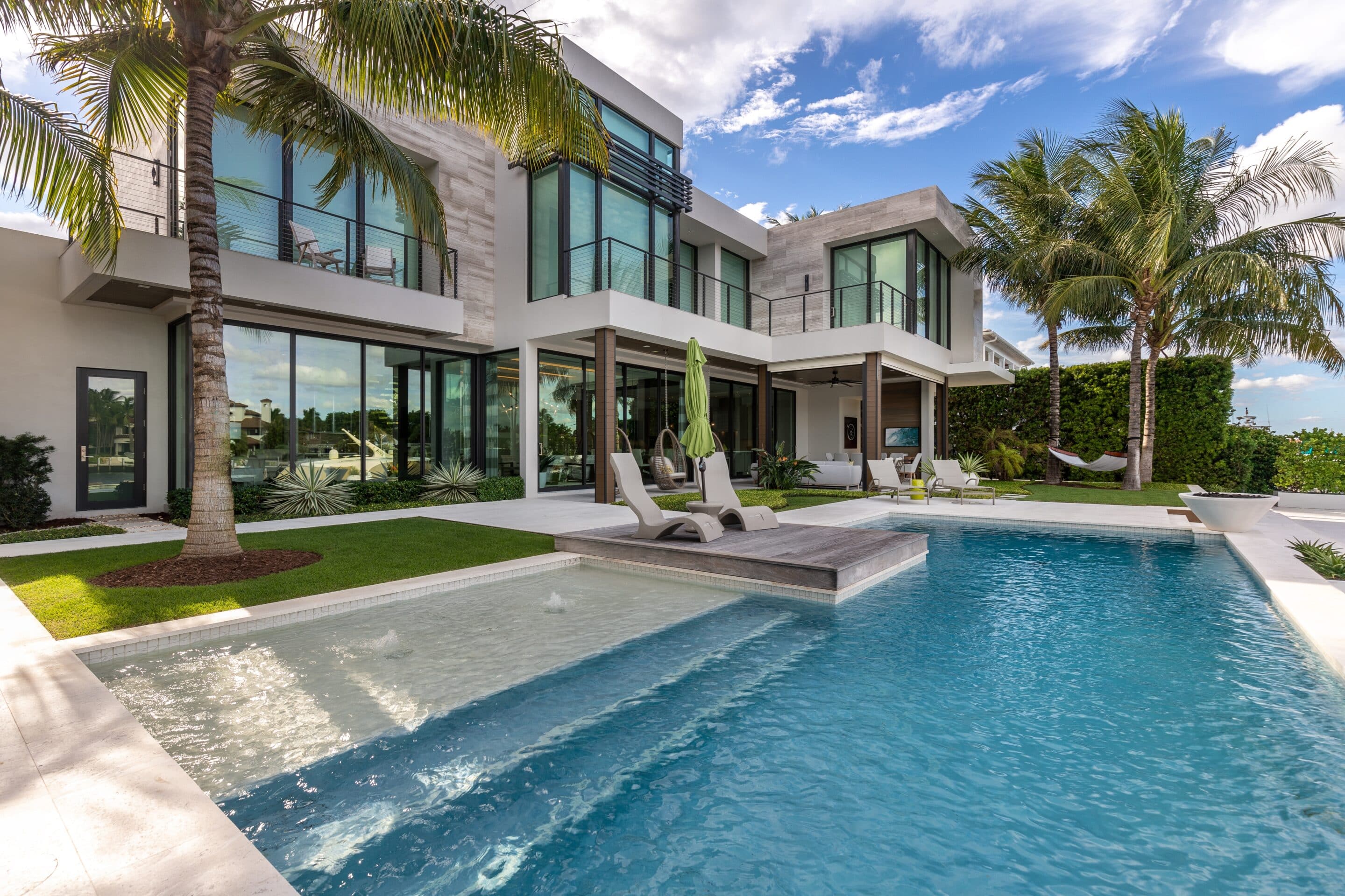 Modern luxury home with a swimming pool and palm trees, emphasizing the need for pool insurance