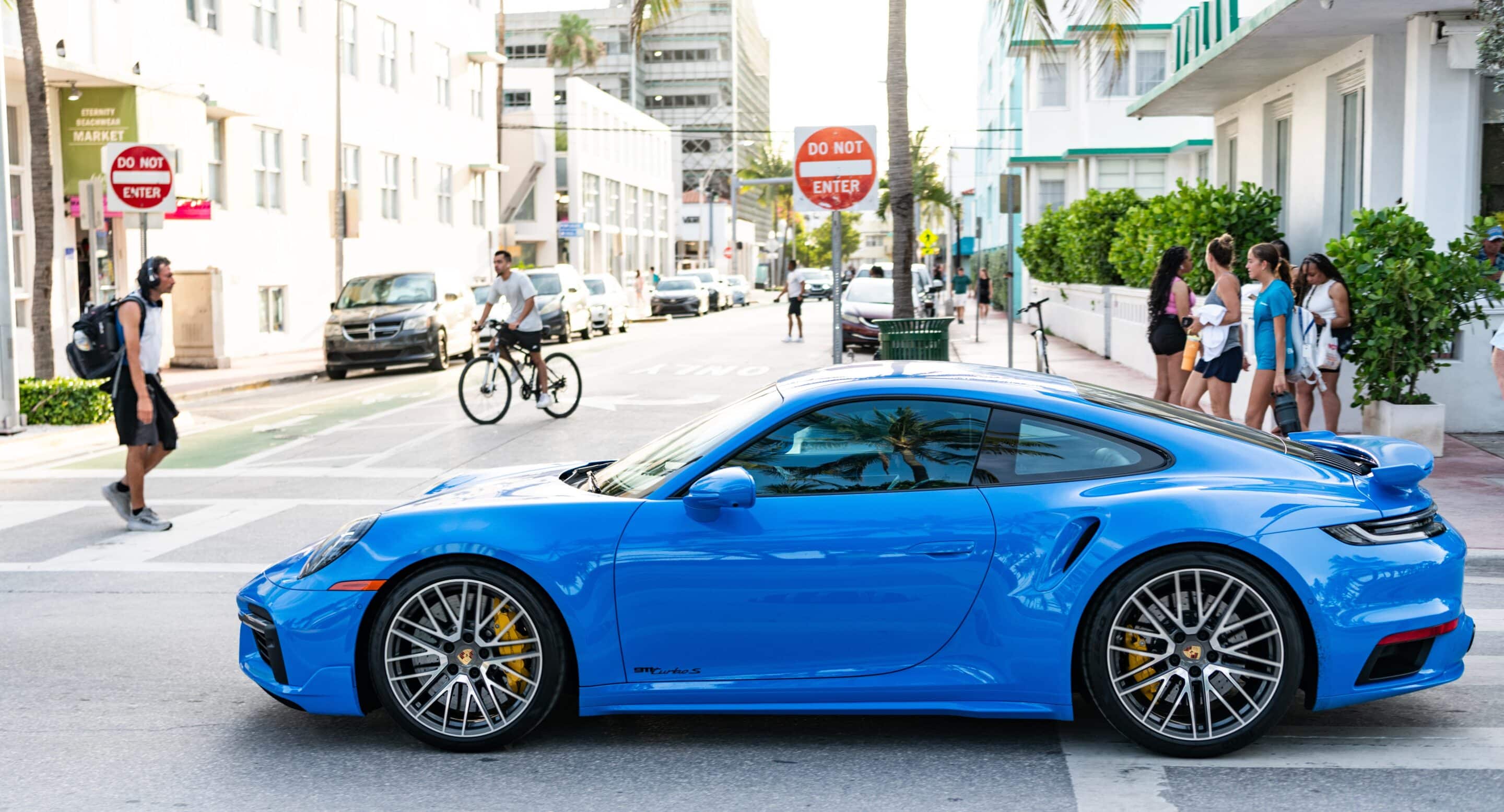 A blue luxury sports car parked on a lively city street, symbolizing the importance of comprehensive coverage from top high-value home insurance companies for premium assets.