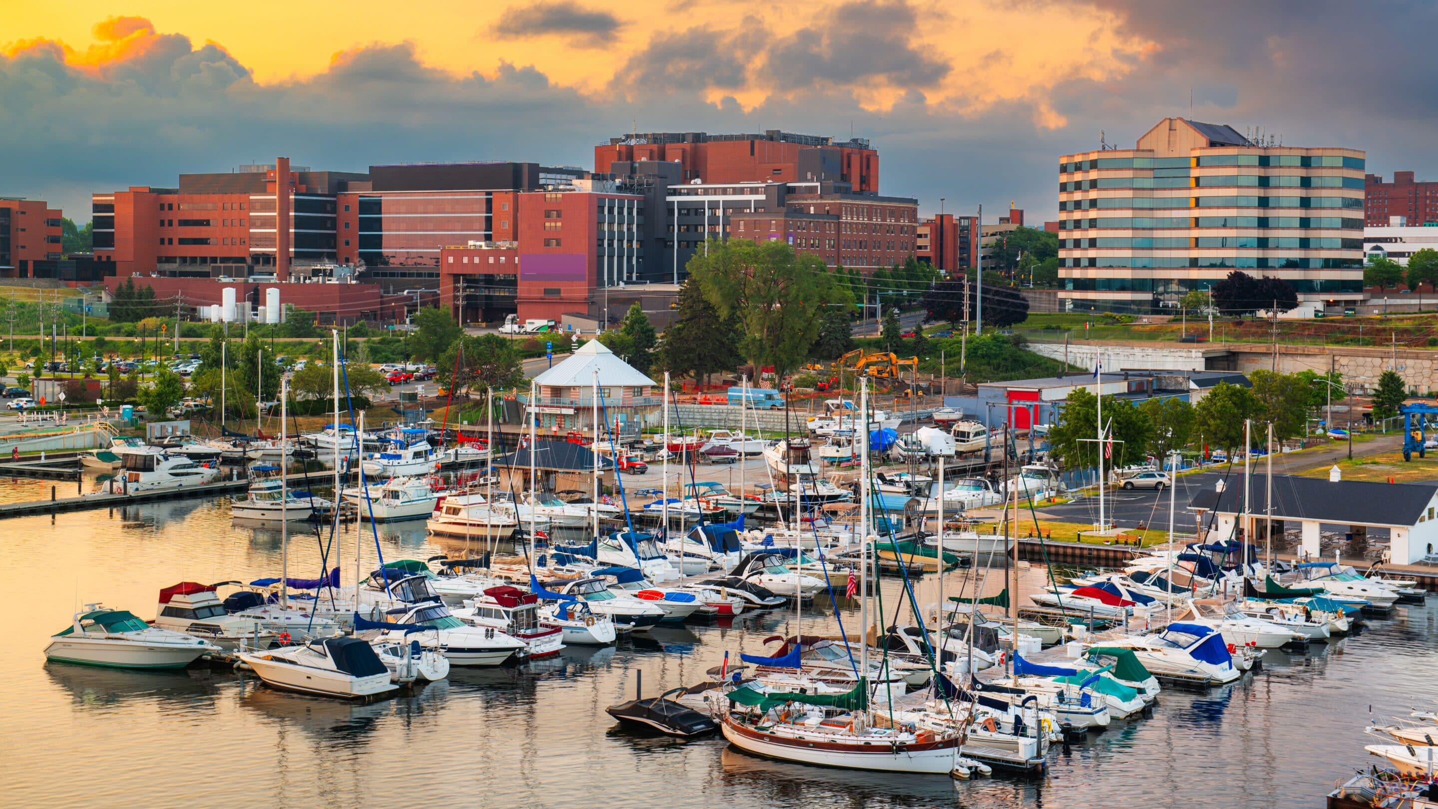 Boats docked at a marina in Erie, Pennsylvania with city buildings in the background at sunset.
