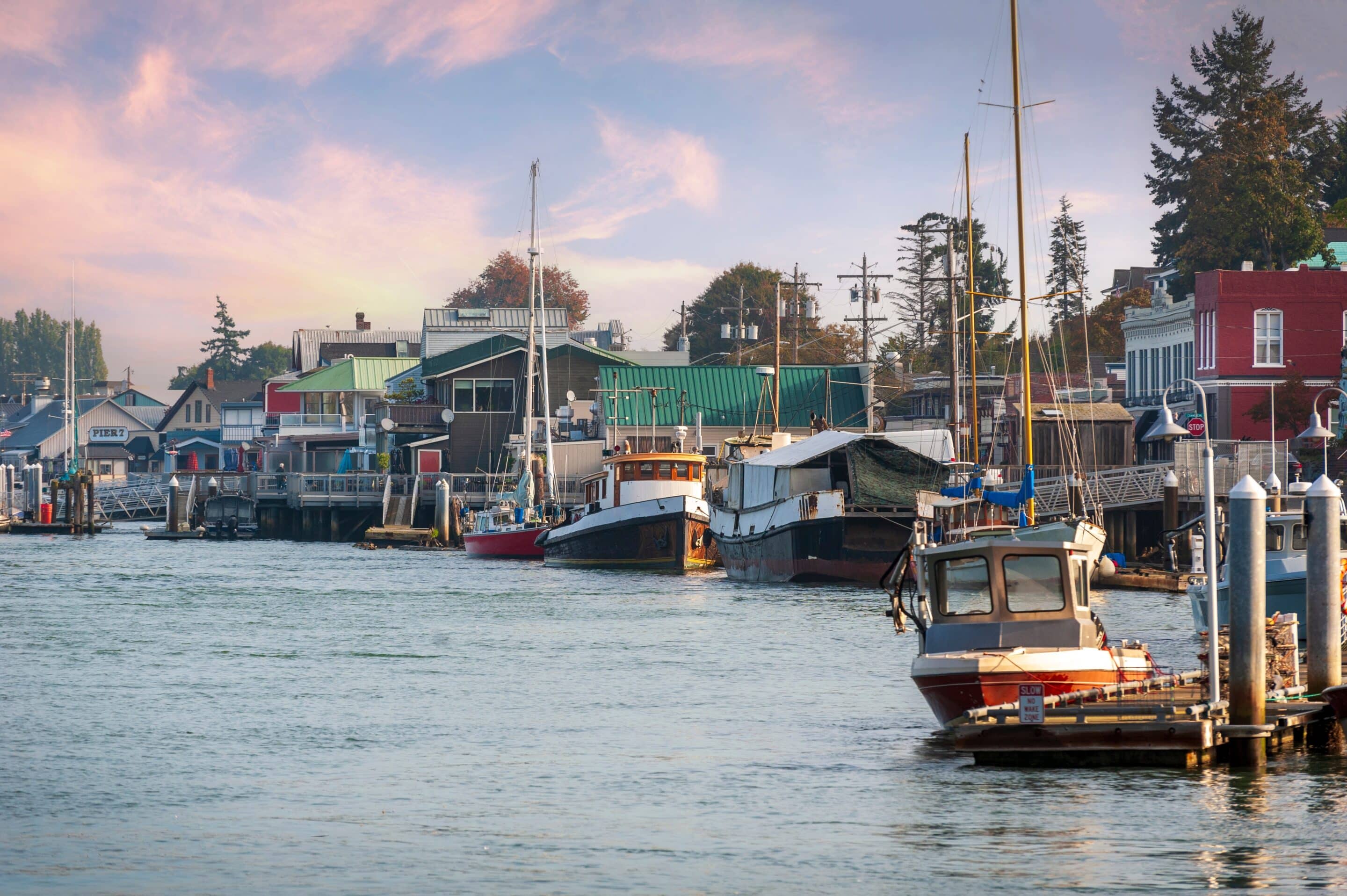 Boats docked along a vibrant waterfront town in Washington state during sunset.