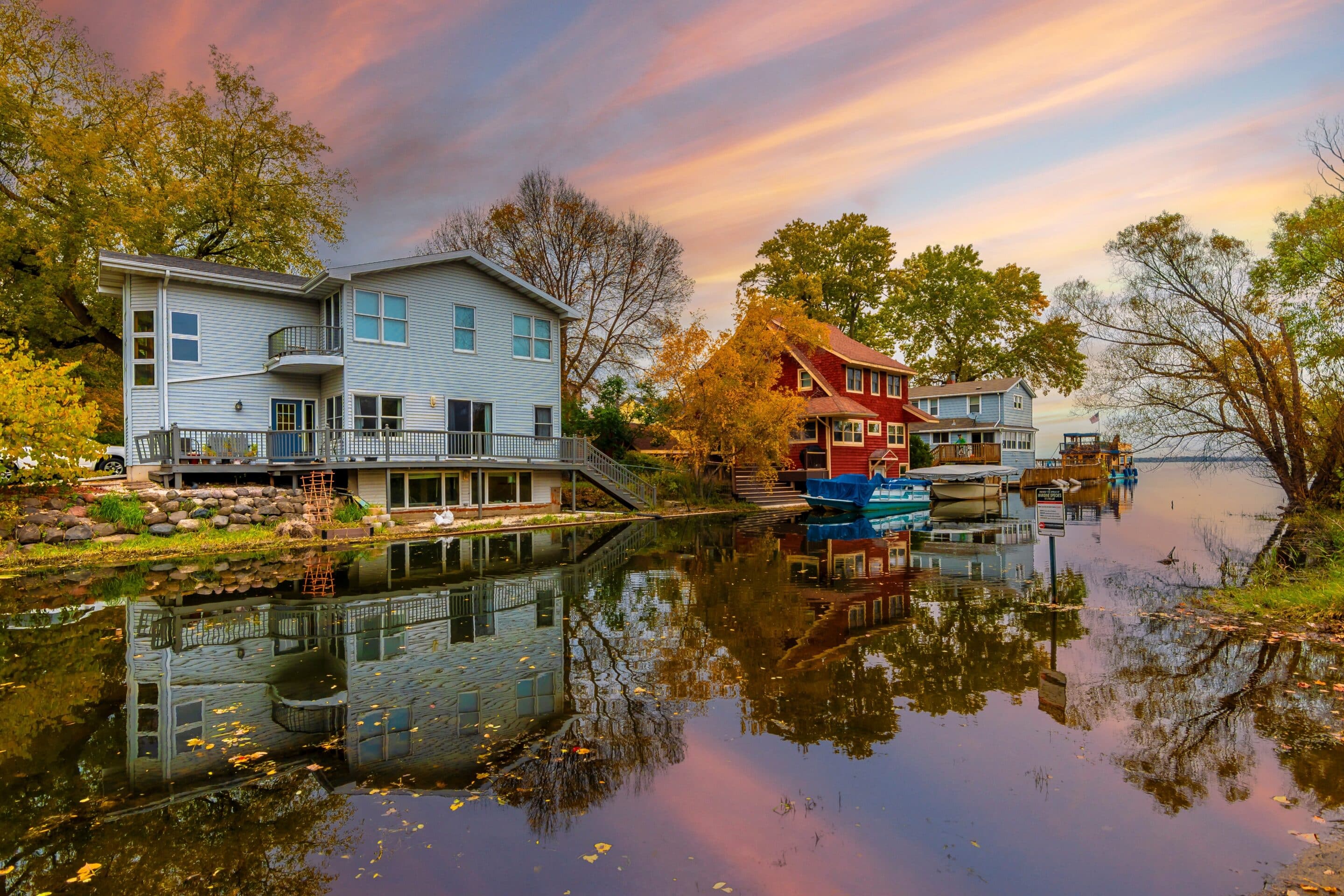 Lakeside homes in Wisconsin reflecting on floodwaters during a colorful sunset.