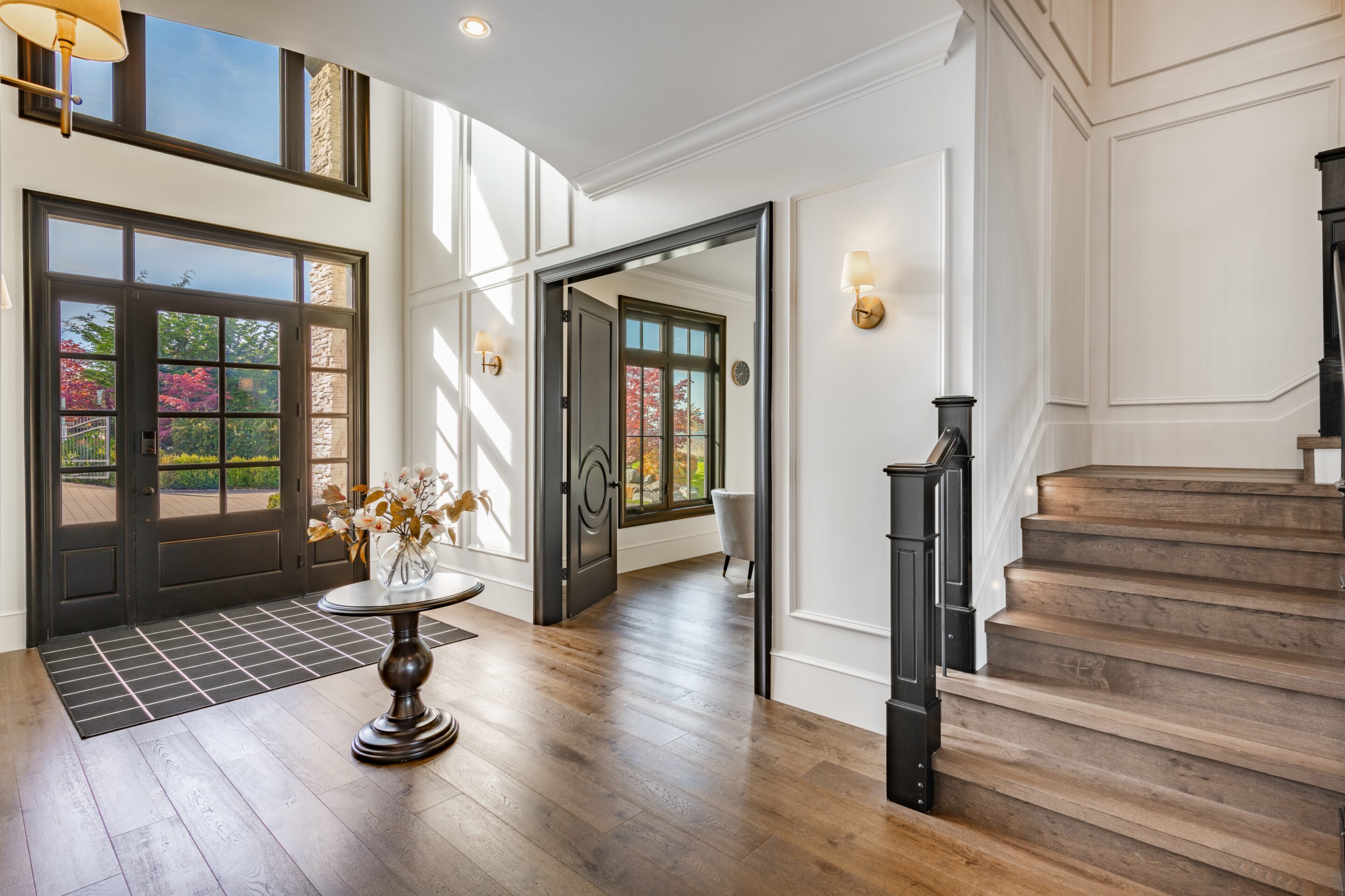 Elegant foyer with wood floors and large windows inside a million-dollar home.