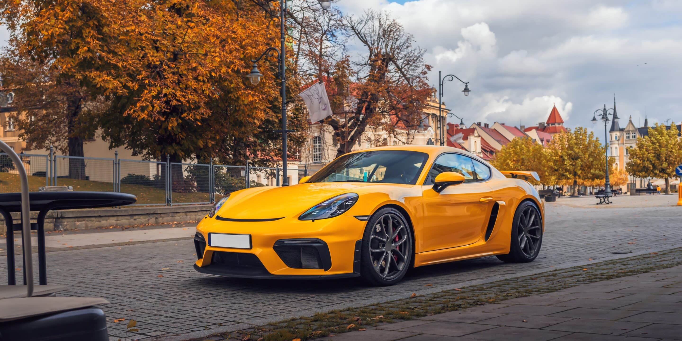 Yellow exotic sports car parked in a European-style city square, highlighting the importance of exotic car insurance and collector car coverage.