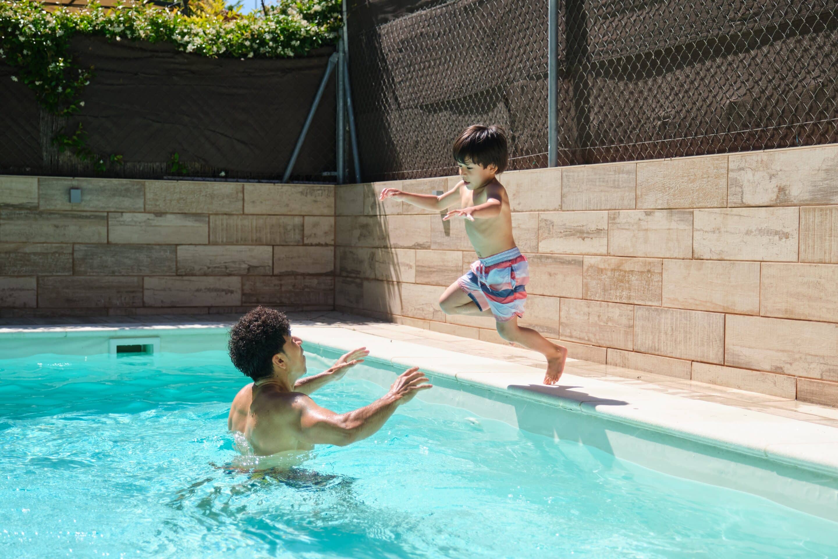 A,Man,And,A,Boy,Are,Playing,In,A,Pool. Pool Diving Board - Homeowners Insurance